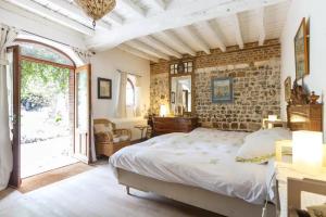 um quarto com uma cama e uma parede de tijolos em Les Herbes Folles em Canouville