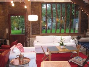 uma sala de estar com sofás brancos e uma mesa em Les Herbes Folles em Canouville