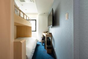 大阪市にあるMeander Osakaのベッド1台、壁掛けテレビが備わる小さな客室です。