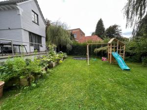 einen Hinterhof mit Spielplatz und Rutsche in der Unterkunft Charmante maison familiale in Kraainem