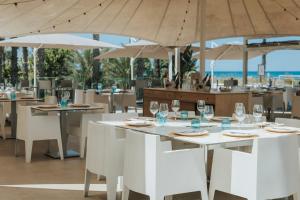 un restaurant avec des tables blanches, des chaises et des parasols blancs dans l'établissement Kiko Park Oliva, à Oliva