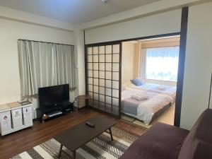 Una sala de estar con una cama y un televisor. en SuYi, en Osaka