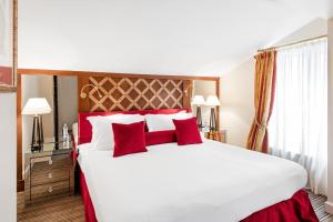 a bedroom with a large white bed with red pillows at Relais & Ch&acirc;teaux Stikliai Hotel in Vilnius