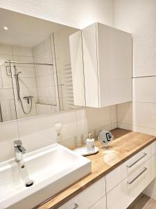 uma casa de banho branca com um lavatório e um espelho em Komfort-Ferienwohnung Zur Alten Post em Wildeshausen