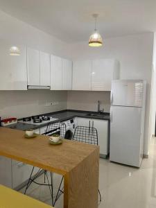 a kitchen with a table and a white refrigerator at Studio Alev POOLview-CaesarResortSpa(North Cyprus) in Perivolia tou Trikomou +4 photos