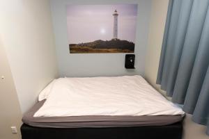 a bed in a room with a picture of a lighthouse at Hvide Sande Inn in Hvide Sande