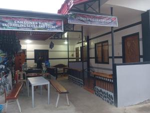 a restaurant with benches and tables in a room at Moalboal Indino's Guesthouse sardines run and sea turtle 1 minute walking distance in Moalboal