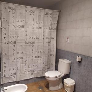 a bathroom with a toilet and a shower curtain with words at La Atalaya de Villalba in Cuenca