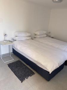 ein Bett mit weißer Bettwäsche und Kissen sowie einem Tisch in der Unterkunft The Oasis Accommodation in Lüderitz