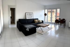 a living room with a black couch and a table at Luminous appartment in Paris with balcony in Aubervilliers