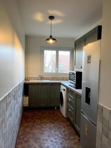 a kitchen with green cabinets and a white refrigerator at Luminous appartment in Paris with balcony in Aubervilliers