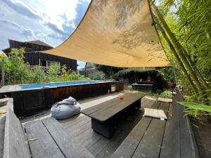 une terrasse en bois avec un banc et un grand parasol dans l'établissement La tiny house de Chaparon, à Lathuile