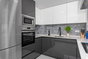 kuchnia z białymi szafkami i czarnymi urządzeniami w obiekcie Apartamento Baltico, 50m to Los Locos Beach w mieście Torrevieja