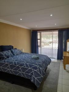 1 dormitorio con 1 cama con edredón azul en Sapphire Guest House en Germiston