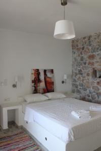 a bedroom with a white bed and a stone wall at Dimitra Studios in Aegiali