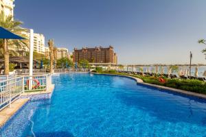 a large pool with blue water in a resort at Bespoke Holiday Homes - Palm Jumeirah- 1 Bedroom Sea View with Pool & Beach Access, Al Haseer in Dubai