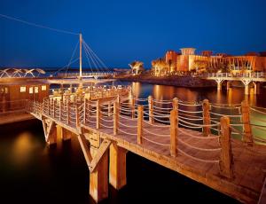 uma ponte de madeira sobre a água à noite em Sheraton Miramar Resort El Gouna em Hurghada
