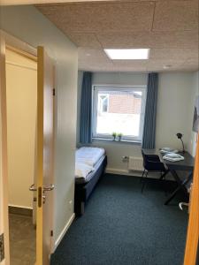 a room with a bed and a desk and a window at Hvide Sande Inn in Hvide Sande