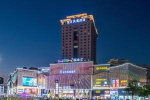 un edificio alto con letreros de neón por la noche en Zhongshan Phoenix By Funyard, en Zhongshan