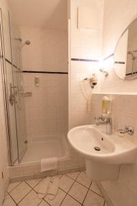 a white bathroom with a sink and a shower at Landhotel Elkemann in Ahaus