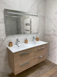 W łazience znajduje się umywalka i lustro. w obiekcie Maison neuve zone coulée verte menant a l'océan w mieście Saint-Gilles-Croix-de-Vie