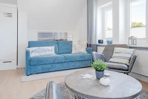 uma sala de estar com um sofá azul e uma mesa em Tanneneck Wohnung 2 em Travemünde