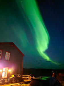 een afbeelding van het noorderlicht in de lucht naast een schuur bij Saudafell Guesthouse in Sauðafell