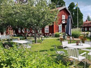 un jardín con mesas y una sombrilla frente a un granero rojo en Stiftsgården Konferens & Hotell en Skellefteå