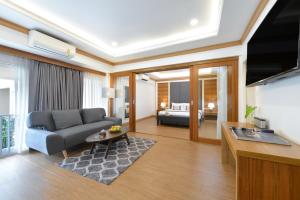 Una sala de estar con un sofá y una habitación con una cama. en The Beverly Hotel Pattaya, en Pattaya South