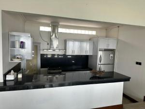 MontongbuwohにあるVilla Pantaiのキッチン(白いキャビネット、黒いカウンタートップ付)