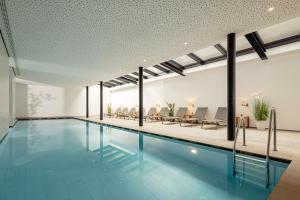 a swimming pool in a building with chairs at Hotel Thalhof am See in Caldaro