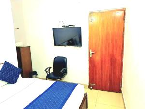 una camera con un letto, una porta e una sedia di Atlas Inn Guest House a Nuova Delhi