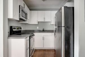 La cuisine est équipée de placards blancs et d'un réfrigérateur en acier inoxydable. dans l'établissement Brookline 2br w public wd nr Fenway groceries BOS-909, à Brookline