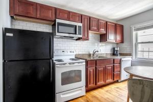 a kitchen with wooden cabinets and a black refrigerator at South Boston 2br w building wd nr seaport BOS-914 in Boston