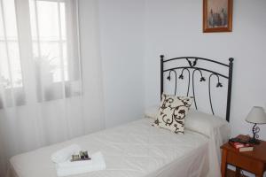 a white bedroom with a bed with a pillow on it at Pensión Algarrobeña in Algarrobo +10 photos
