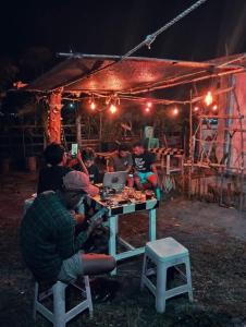 a group of people sitting around a picnic table at night at Sirus Base Camp Tagulandang in Kisihang