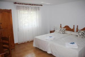 a bedroom with a white bed and a window at Pensión Algarrobeña in Algarrobo