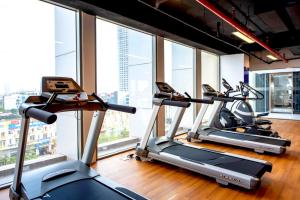 a row of treadmills in a gym with windows at Wyndham Garden Hanoi in Hanoi