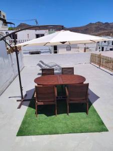 Casa Paula في لاس بلايتاس: طاولة خشبية مع كراسي ومظلة على الفناء