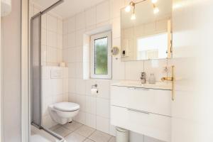 Un baño blanco con inodoro y lavabo. en Bungalow Flora, en Westerland 22 fotos más