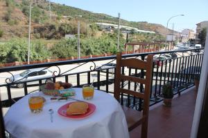 a table with a plate of food and drinks on a balcony at Pensión Algarrobeña in Algarrobo