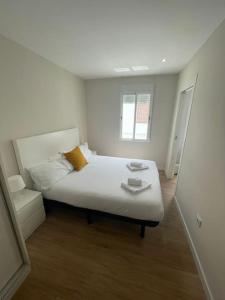 a small white bedroom with a bed and a mirror at Apartamento céntrico de diseño en calle Tres Forques,Valencia in Valencia