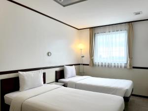 a hotel room with two beds and a window at Toyoko Inn Cebu in Cebu City