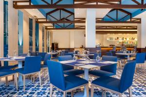 un restaurant avec des tables et des chaises bleues ainsi qu'un bar dans l'établissement Los Amigos Beach Club, à La Cala de Mijas