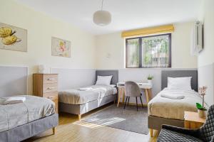 a bedroom with two beds and a desk and a chair at P&O Apartments Juhasów - Wawer in Warsaw