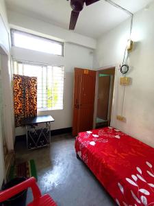 1 dormitorio con cama roja y ventana en Ajanta Lodge, en Guwahati