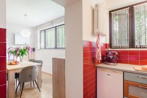 a kitchen with red tiles on the walls and a table at P&O Apartments Juhasów - Wawer in Warsaw