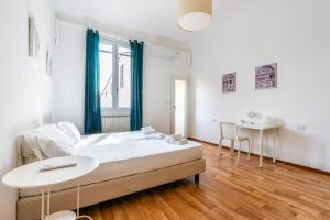 a white bedroom with a bed and a table at Alfani 63 Apartment in Florence
