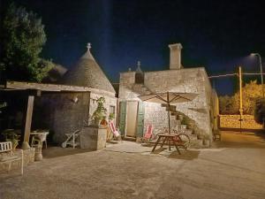 a stone building with a table and an umbrella at Trullo Galeotto in Martina Franca
