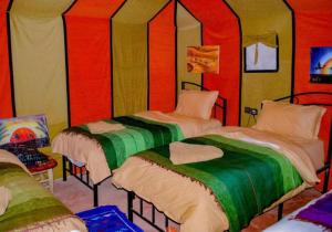 two beds in a room with red and green at Sahara traveling camp in Merzouga
